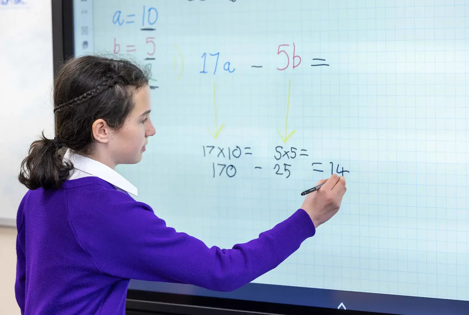 A King's Magna pupil writing on the digital whiteboard in maths class