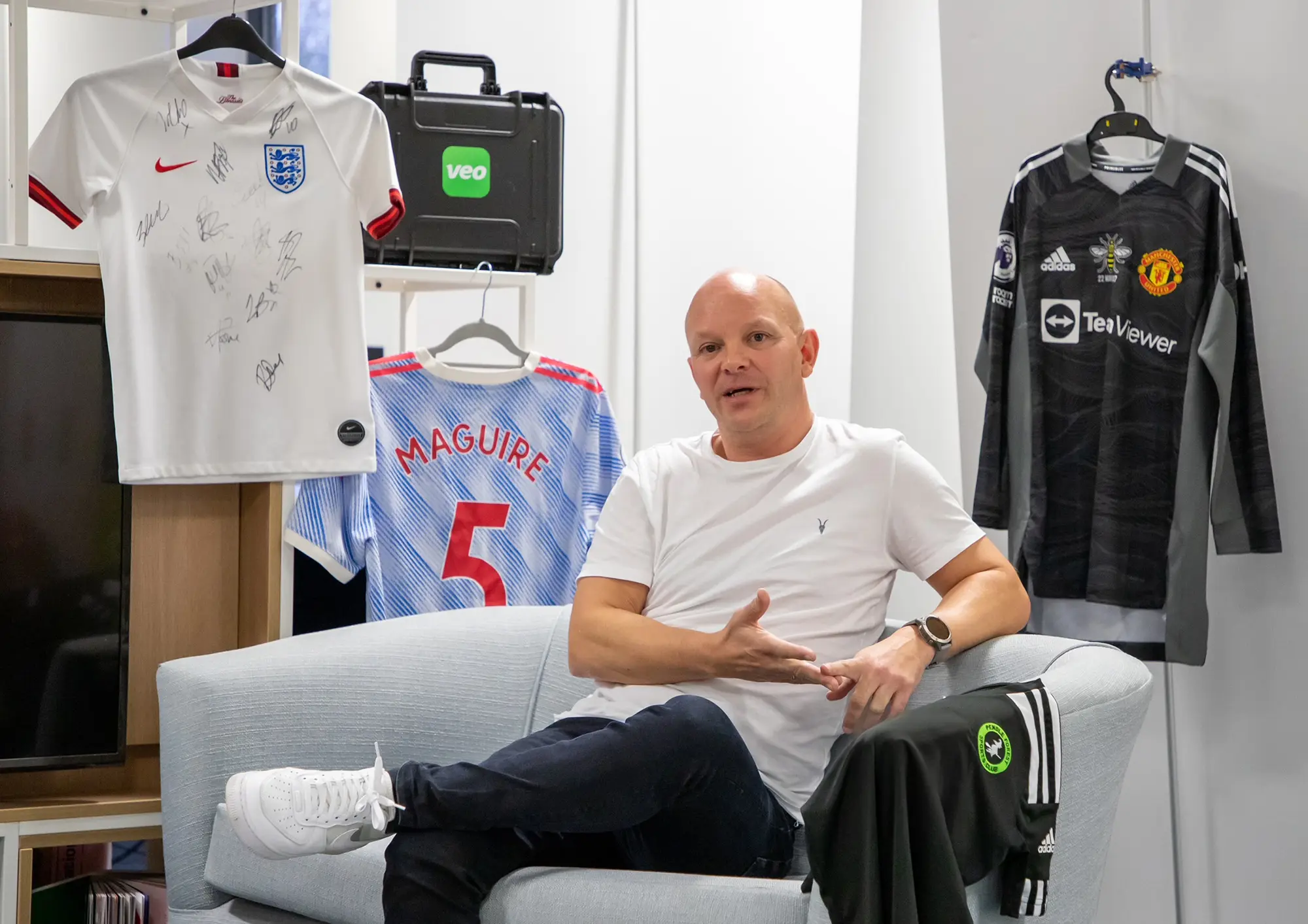 David Horrocks sitting with signed t-shirts. 