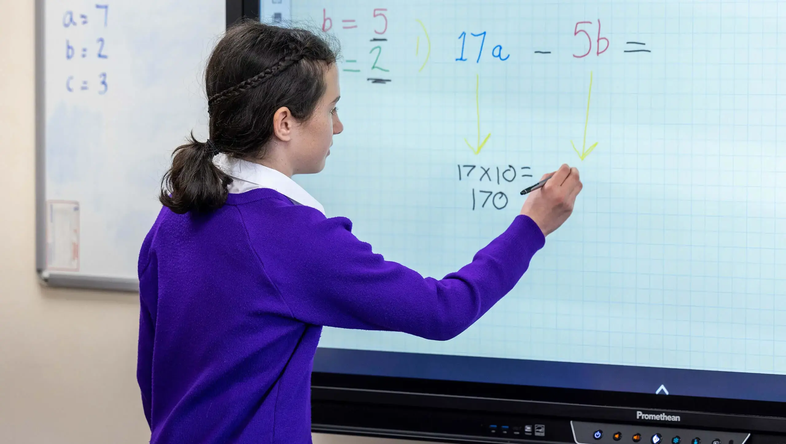 Queen Ethelburga's student in class writing on the digital whiteboard